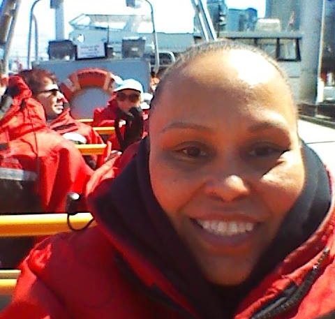 Sylvia smiles in red jacket on boat.