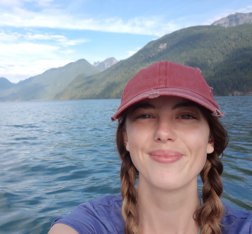 ID: Skye smiles with red ballcap and sunny mountain lake backdrop