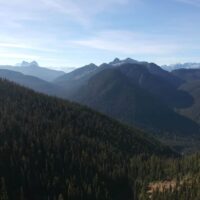 ID: Forested mountains plunge into river valley on blue skied day