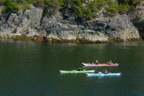 three colourful kayaks by rocky islet
